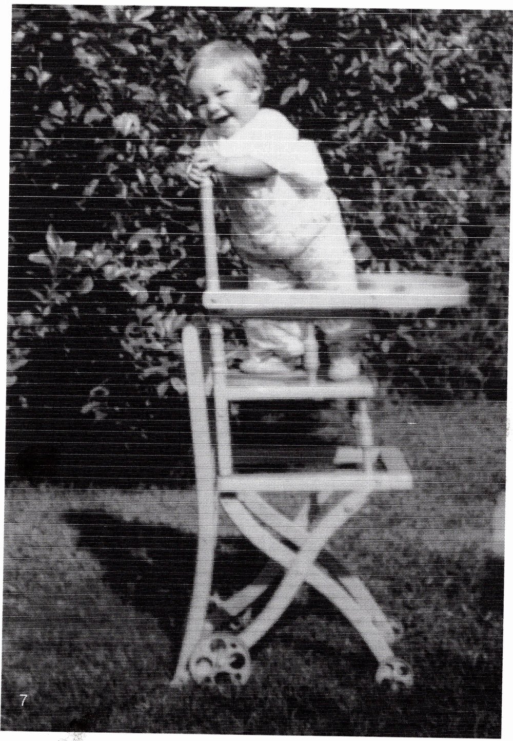 Derek Distel as a baby, standing in a wooden high chair in a garden